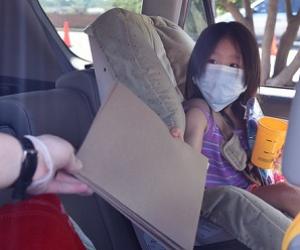 girl in car seat being handed a brown folder